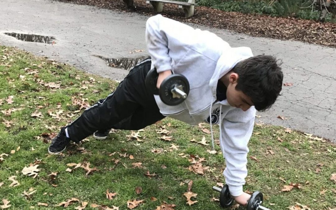 Boy with dumbbells in park